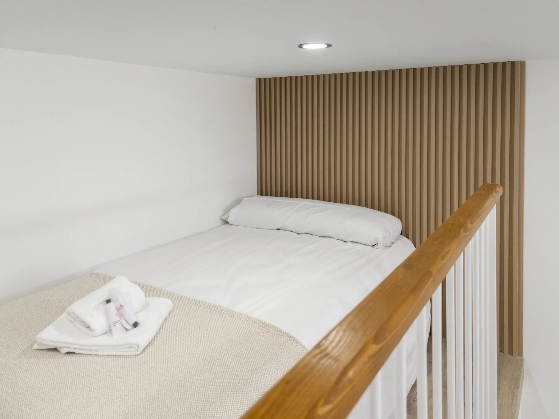 Bed on the mezzanine with wooden railing